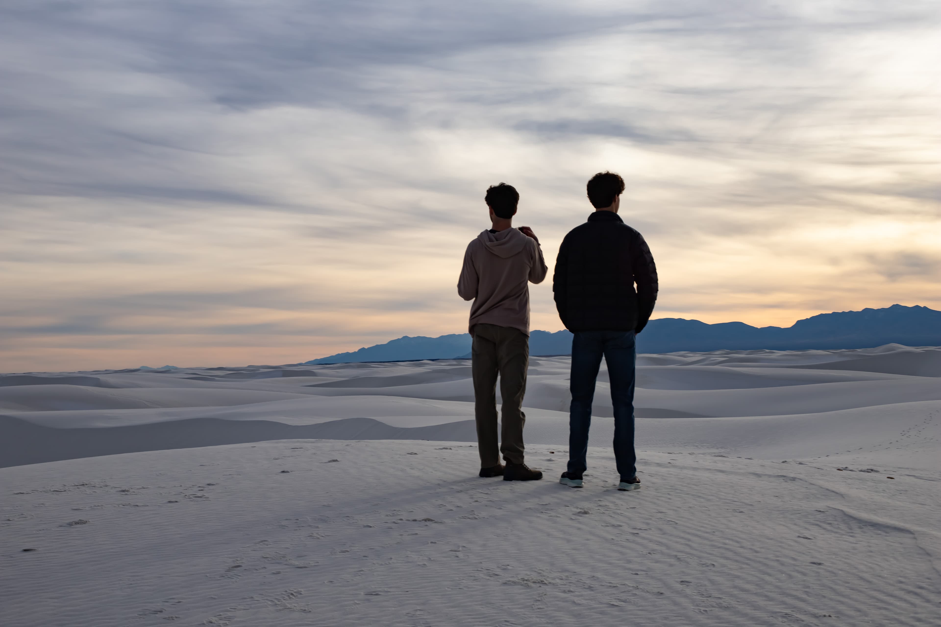 Two people looking out over White Sands at sunset